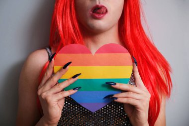 Gri arka planda gökkuşağı bayrağı taşıyan tanınamaz seksi transseksüel kişi. LGBTQ eşcinseli.