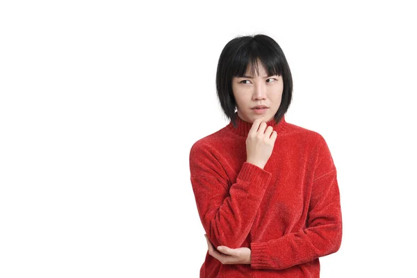 年轻的亚洲女人带着沉思的表情和体贴的脸摸着下巴 穿着冬日的红色毛衣 背景是白色的 — 图库照片
