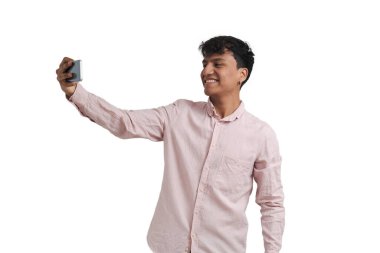 Genç Perulu adam akıllı telefonuyla selfie çekiyor. Beyaz arkaplan üzerinde izole edilmiş.