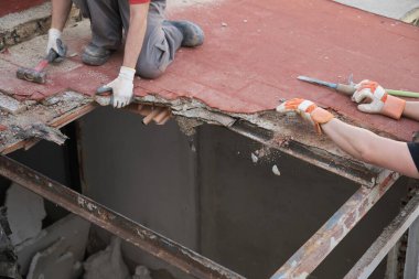 Tanımlanamayan iki duvar ustası bir çekiç kullanarak evin tavanını yıkıyor..