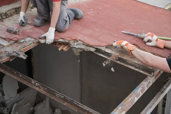 Tanımlanamayan iki duvar ustası bir çekiç kullanarak evin tavanını yıkıyor..