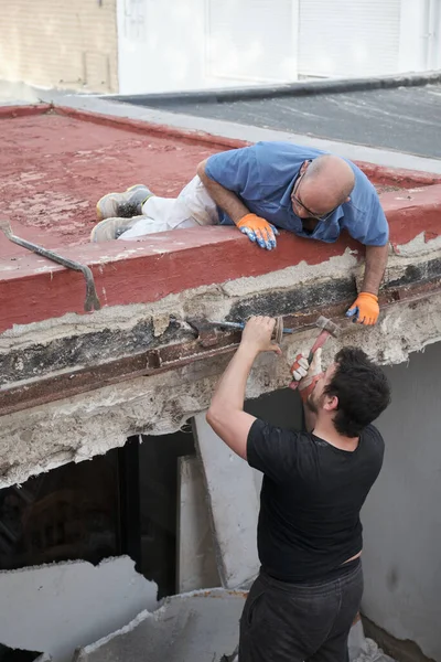 İnşaat evinde eski metal kirişleri söken iki duvar ustası..