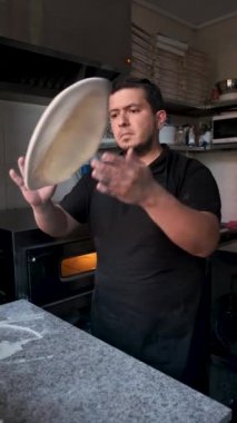 Latin man preparing dough for pizza in a restaurant kitchen. Pizzeria.