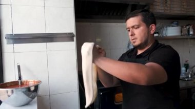 Latin man preparing dough for pizza in a restaurant kitchen. Pizzeria.