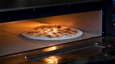 Pepperoni pizza cooking into the oven in a restaurant kitchen. Pizzeria.