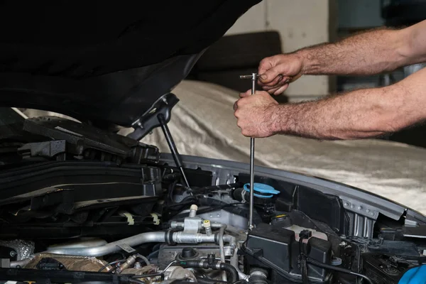 Car mechanic hands replacing engine throttle body. Mechanics workshop.