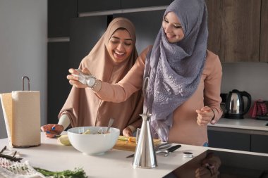 Modern mutfakta salataya tuz ekleyen iki müslüman kadın..