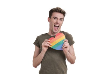 Young caucasian man shouting with joy at camera with lgbt flag heart, isolated on white background.