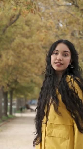 若いラテン系の女の子が振り向く カメラを見て 秋に通りで笑顔 — ストック動画