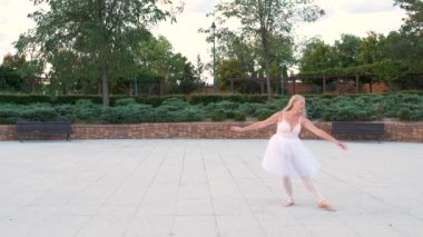 Caddedeki parkta bale yapan olgun, gülümseyen bir kadın..