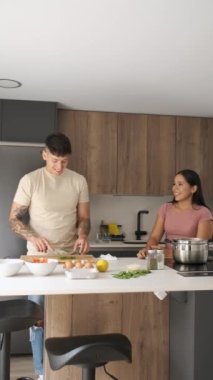 Mutfakta yemek tarifi hazırlamak için kişniş kesen ve tavada yemek pişiren iki genç Latin..