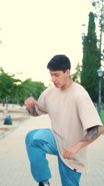 Ekvadorlu dövmeli genç bir adam koreografi yapıyor ve parkta sokakta gülüyor..
