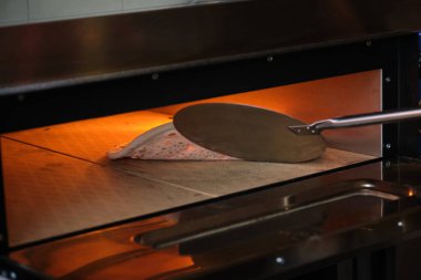 Pizzanın bir restoranın mutfağında fırında pişirilip pişirilmediğini kontrol ediyorum. Pizzacı..