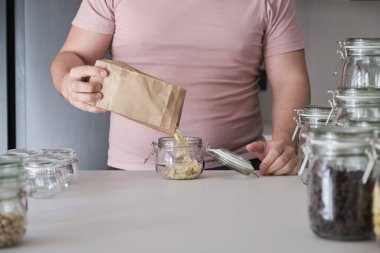 Tanınmayan Latin bir adam bir kavanozu kağıt torbadan kesilmiş bademlerle dolduruyor. Toplu teslimatta yemek..