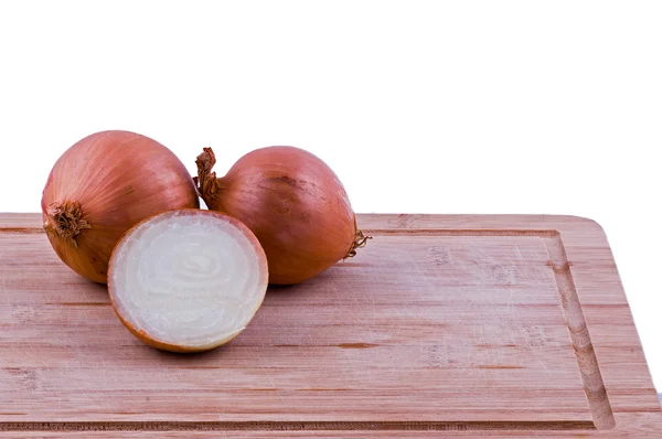 Dos cebollas llenas y media sobre tabla de cortar — Foto de Stock