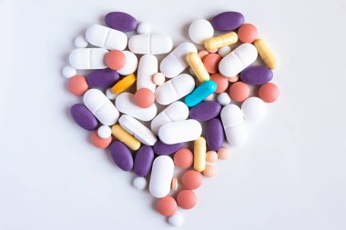Beyaz bir masada eczane geçmişi. Kalp şeklinde farklı ilaç ve kapsülleri kapatın..