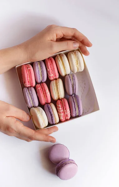 Pastel rosado y violeta pastelería francesa macarrón postre en la caja con las manos —  Fotos de Stock