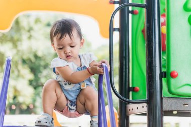 Gülümseyen güzel bir kız, Macera Parkı 'ndaki oyun parkında mutlu bir şekilde tırmanıyor..