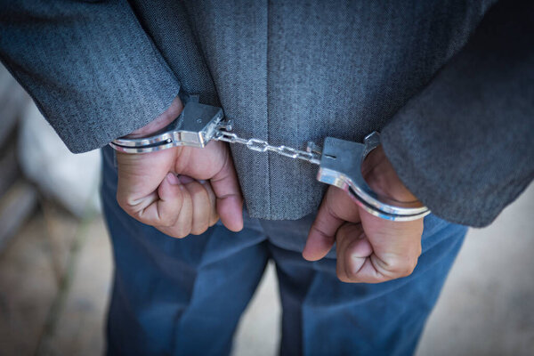 Арестованный бизнесмен в наручниках с руками за спиной
.