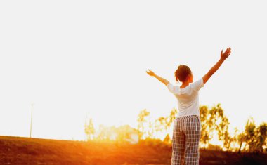 Siluet tarafı kızı yukarı bakıyor Sıcak ışık ve gökyüzü ile yenilenmiş hissediyorum.