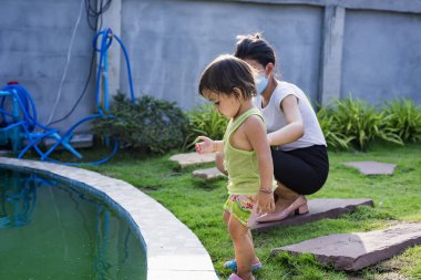 Anne ve oğlu evin arkasındaki bahçede koi balığını izliyorlar. Aile eğlence aktivitelerini rahatlatma konsepti.