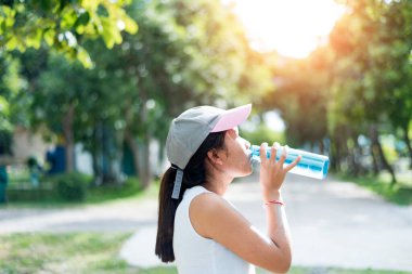 Koşu, sağlık ve spor konseptinden sonra su içen Asyalı genç kadın.