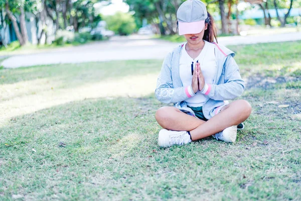 Young Asian woman practicing yoga pose at the park , yoga and meditation have good benefits for health. Photo concept for Yoga Sport and Healthy lifestyle.