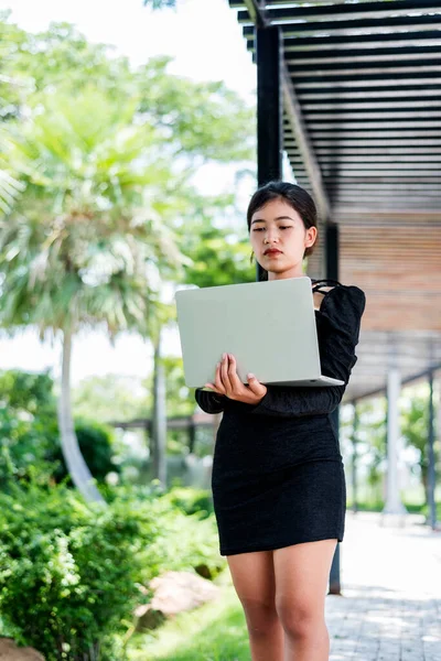 Beautiful businesswoman in black working on laptop . Comfortable work or remote work concept.
