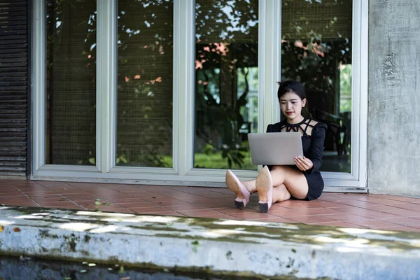 Beautiful businesswoman in black working on laptop . Comfortable work or remote work concept.