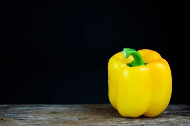 one yellow sweet bell pepper on black background
