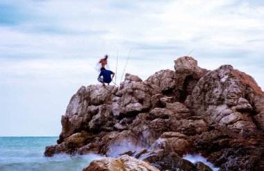 Deniz kıyısındaki kayalıklarda balıkçı.