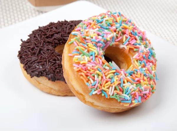 Donut colorido y chocolate en plato blanco Imagen de archivo
