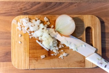 Kesme tahtasında doğranmış taze soğan. Tepeden aşağı düz manzaralı büyük bir mutfak bıçağıyla.