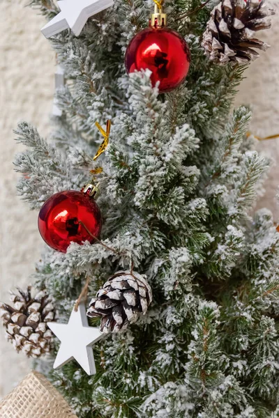 白い冬の雪で覆われたコーンと緑の松の枝に赤い泡と星とお祭りのクリスマスの装飾は 完全なフレームビューを閉じます — ストック写真