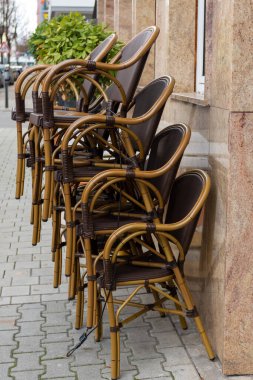 Şehirdeki bir restoranın önünde düzgünce kaldırıma dizilmiş kamış sandalyeler.