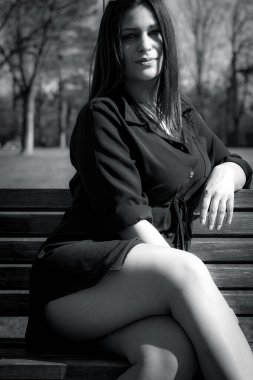 Şehir parkında bir bankta oturan zarif, güzel bir kadın. Siyah beyaz bir resim gibi.