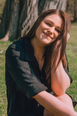 Şehir parkında siyah bluzlu çekici bir genç kadın.