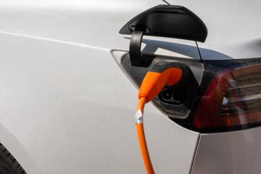 Şarj istasyonunda şarj edilen beyaz bir elektrikli araba.