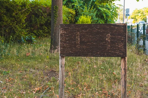 an empty wooden sign in a city park in the summer