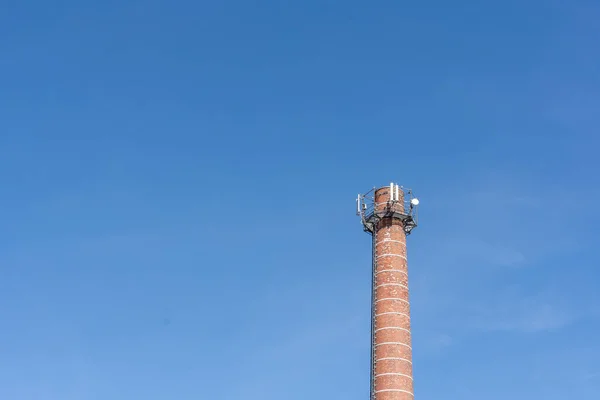 a chimney with radio equipment with blue sky in the background