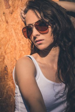 a portrait of a woman with red sunglasses in front of a wooden wall