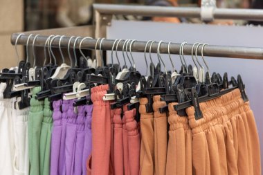Moda mağazasında renkli pantolonlu bir elbise askısı.