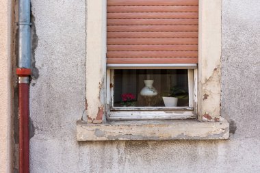 an old window with half-open roller shutters in the city