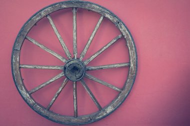 an old wooden wheel on a red wall for decoration with text free space right