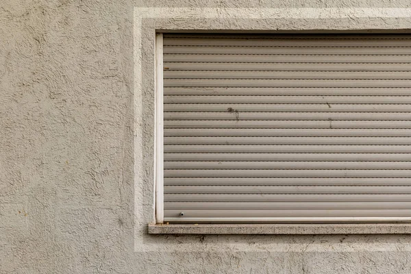 a window with closed roller shutter in the city