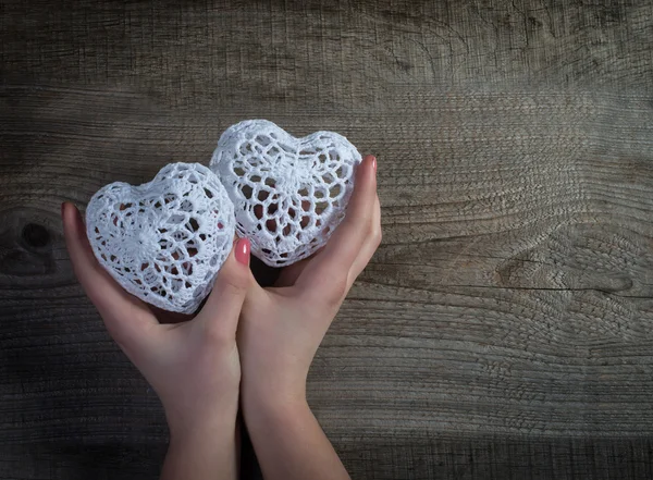 Woman hands holding white lace hearts on old wood background. Valentine's day. — Stock Photo, Image