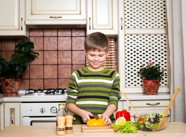 Uśmiechnięty chłopiec przygotowanie sałatka w kuchni. Zdrowa żywność. — Zdjęcie stockowe