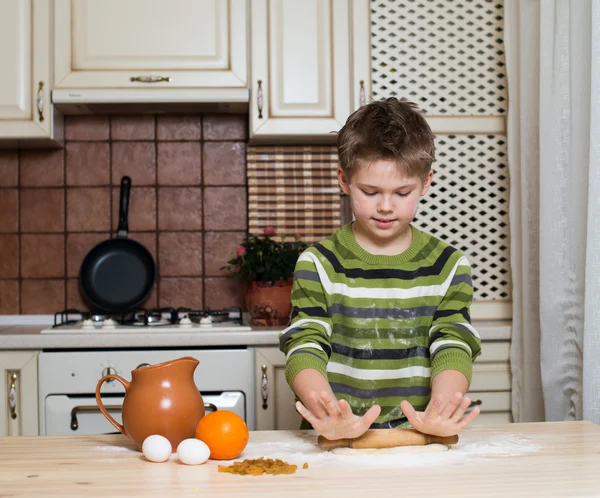 Mały chłopiec w kuchni przygotowanie ciasta za pomocą walcowania. — Zdjęcie stockowe