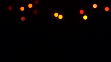 Siyah arka plandaki dekoratif çelenk üzerinde yanıp sönen bokeh ışıkları. Göz kırpan yeşil, mavi, kırmızı ve sarı. Kavram: Noel, Yeni Yıl, Tatil.