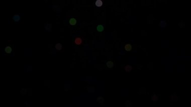 Siyah arka plandaki dekoratif çelenk üzerinde yanıp sönen bokeh ışıkları. Göz kırpan yeşil, mavi, kırmızı ve sarı. Kavram: Noel, Yeni Yıl, Tatil.